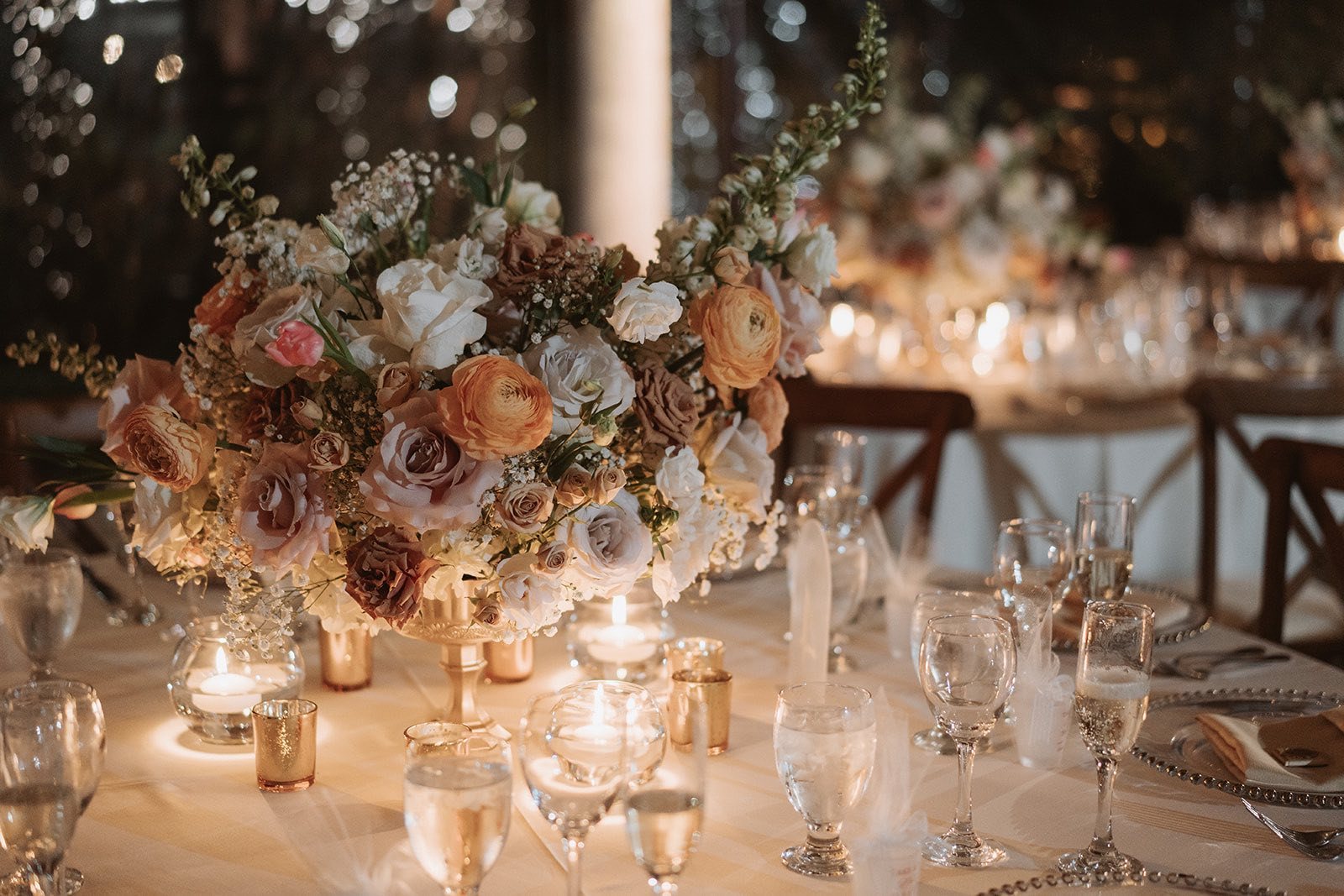 Warm candlelit table arrangement with peach and ivory flowers